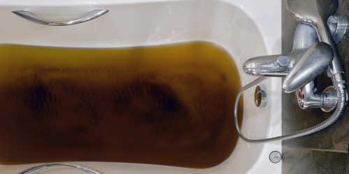 A bathtub filled with dirty water due to a clogged sewer pipe, close-up